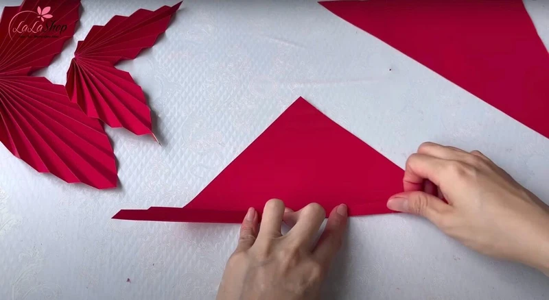 Sử dụng giấy hình tam giác để gấp quạt hình chiếc lá